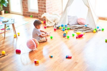 Beautiful toddler boy sitting on the floor playing inside  tipi at kindergarten © Krakenimages.com