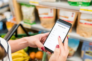 Female Customer Using Mobile Phone In Supermarket