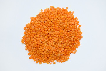 Red lentils on a white background. Orange raw grains of lentils slide top view.