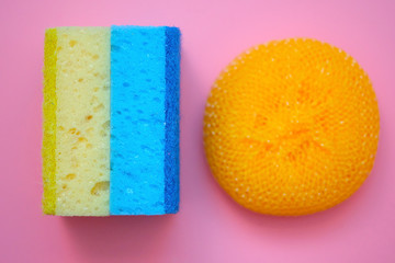 Two washcloths and a plastic brush for washing dishes. Bilateral foam rubber washcloths on a pink...