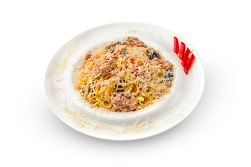 Spicy tuna spaghetti with red dried chillies and sweet basil leaves on white dish.