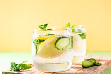 Healthy refreshing summer cocktail or mocktail without alcohol with lemon and cucumber. Summer detox drink on fresh green background, healthy living, top view