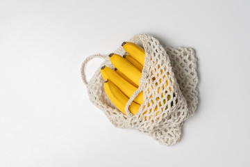 the bunch of fresh banana in mesh eco bag on the shelf, natural organic food, trendy concept