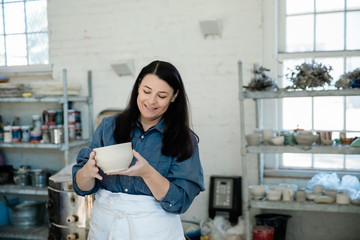 Creative Pottery Cermanic artist holding a piece of unfinished clay pottery in an art loft studio