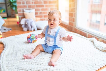 Beautiful toddler sitting on the blanket at kindergarten