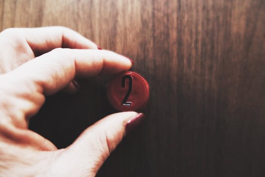 CROPPED IMAGE OF WOMAN HOLDING A Number Two Pin