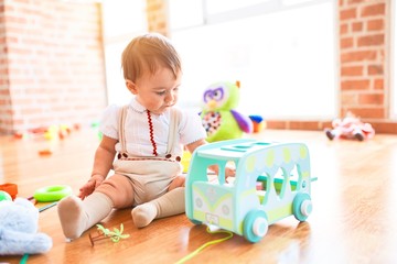 Adorable toddler playing around lots of toys at kindergarten