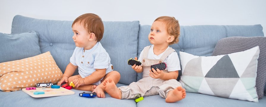 Beautiful toddlers sitting on the sofa playing with toys at home