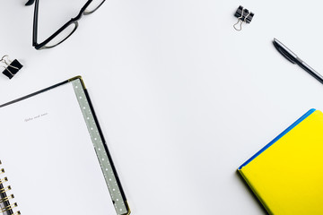 Minimal work space with a yellow notebook, a black pen and glasses on white background. Top view , flat lay