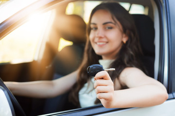 Proud female driver with start engine car key just after passing driving examination in driving school