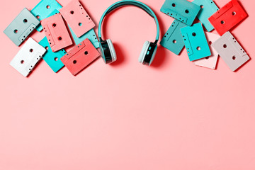 Painted audio cassettes in bright colors and blue earphones on pastel background, copy space, top...