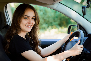 Obraz na płótnie Canvas Cheerful female just after receiving car licence. Happy woman driver drives her new car with friends and feels pleased