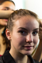 Face of Young Woman Looking at Camera while Having Hair Braided