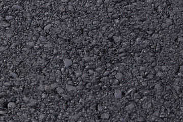 Dark black background from adjoined rolled asphalt. Modern technologies of solid pavement for vehicles and pedestrians. Elements of the construction of highways. The granular structure of small stones