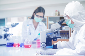 scientist or doctor working research in medical laboratory with microscope and test tube