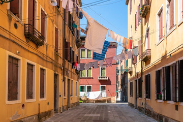 Fototapeta na wymiar Venice. Colorful laundry is dried on the clotheslines between the houses. Authentic Venetian street in sunshine. Ancient Italian city. Lifestyle of people. Travel Tourism in Europe.
