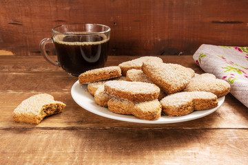 Shortbread cookies in the shape of a heart lie in a white plate. The plate stands on a wooden table.