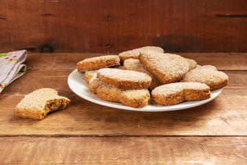 Shortbread cookies in the shape of a heart lie in a white plate. The plate stands on a wooden table.