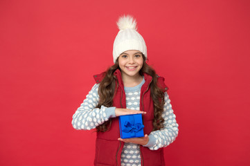 Winter holidays. Happy kid in winter outfit hold gift box red background. Wish list. Holidays season. Happy childhood. Christmas gifts. Vacation souvenirs concept. Gift for female. Xmas gift idea