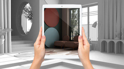 Hands holding tablet showing colored classic living room, total blank project background, augmented reality concept, application to simulate furniture and interior design products