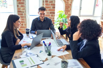 Group of business workers smiling happy and confident. Working together with smile on face  using laptop and speaking at the office