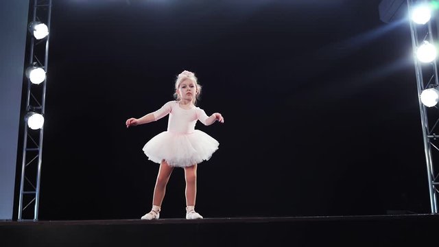 Little girl ballerina Caucasian appearance in a pink tutu dances on stage. Children. Slow motion. Shooting on the Steadicam