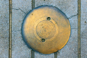Yellow manhole cover or pipe cap on the footpath,abstract wallpaper.