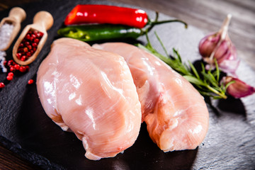Raw chicken breasts with spices on black stone plate