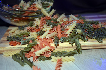 Multi-colored pasta on a wooden board. Food.