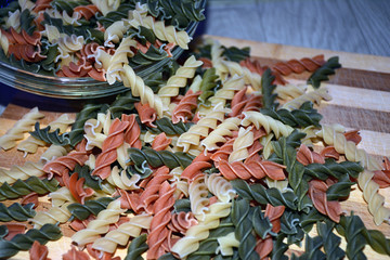 Multi-colored pasta on a wooden board. Food.