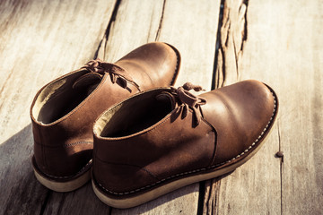 Brown stylish boots on wood background,  retro color