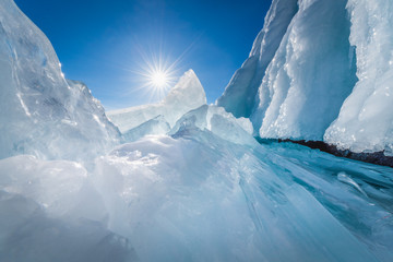 Natural ice cave in bottom view with blue sky and sun at Baikal lake, Siberia, Russia.