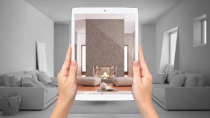 Hands holding tablet showing cosy living room with fireplace, total blank project background, augmented reality concept, application to simulate furniture and interior design products