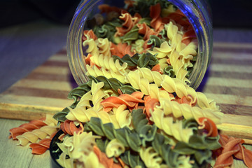 Multi-colored pasta on a wooden board. Food.