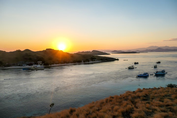 Fototapeta premium A view on a the morning sun rising over an island formation in Komodo National Park, Flores, Indonesia. Golden hour over the islands and sea. Idyllic landscape. New day beginning. Chocolate hills.