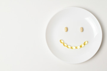 Fototapeta premium Multivitamin and fish oil capsules in a shape of smile emoji.