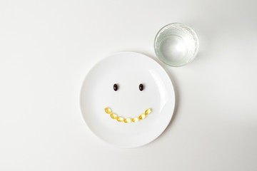 Fototapeta na wymiar Astaxanthin and fish oil forming smile on a white plate.