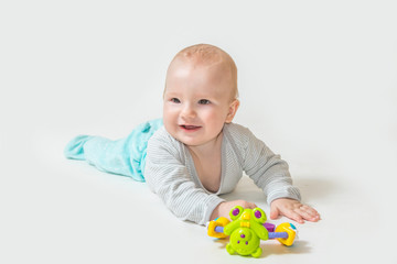 Smiling  baby boy is lying on white background and showing a toy. All potential trademarks are removed. 