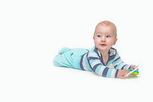 Cute baby boy is lying on white background holding a toy. Photo contains a lot of free space for your use. All potential trademarks are removed. 