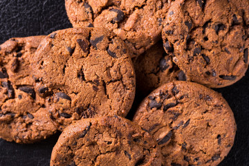 Appetizing chocolate chip cookies with slices of raisins on a black background.