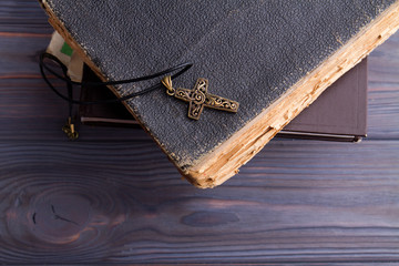 Christian cross on old aged coverbook. Necklace with crucifix and bible books.