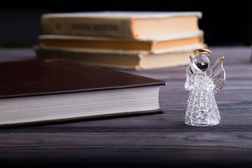 Glass angel and books. Close-up. Holy books concept.