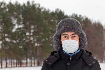 Fototapeta na wymiar Sick man wearing facial mask in winter, outdoor. Russia. Viral diseases, respiratory protection.