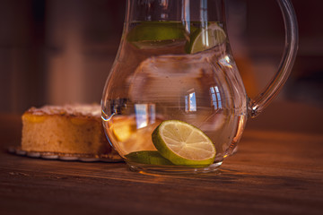Still life with glass of water with lemon and apple pie on wooden table. Travel destination Tuscany, Italy