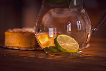 Still life with glass of water with lemon and apple pie on wooden table. Travel destination Tuscany, Italy