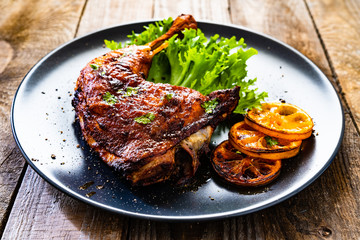 Barbecue chicken thigh with vegetables on wooden background