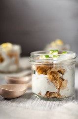 milk yogurt with cereal and slices of lemon in a glass jar with wooden spoons on a wooden light background, light diet breakfast, healthy food