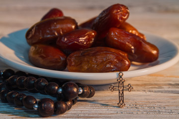 Pile of date fruits, religious cross and rosary. Closeup.