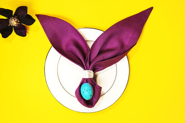 Beautiful Easter table setting with egg, purple napkin Easter Bunny on white plate.