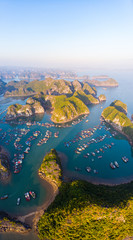 Aerial sunset view of Lan Ha bay and Cat Ba island, Vietnam, unique limestone rock islands and karst formation peaks in the sea, floating fishermen villages and fish farms from above. Clear blue sky.